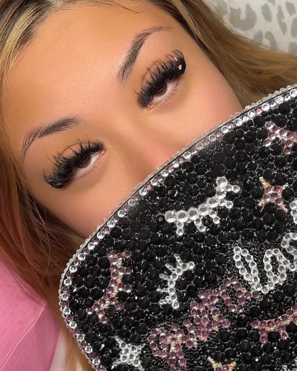 Client with wispy lash extensions behind the rhinestone gueralashes bag